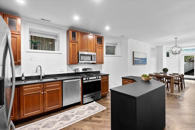 506 W Oakdale Ave Unit 1, Chicago, IL 60657 - kitchen with stainless steel appliances, dark countertops, brown cabinetry, dark wood-style flooring, and decorative backsplash