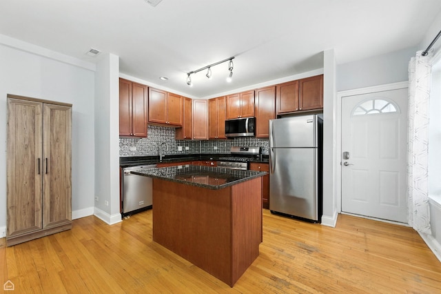 2611 W Rosemont Ave Unit A, Chicago, IL 60659 - kitchen featuring appliances with stainless steel finishes, a kitchen island, backsplash, light wood-style flooring, and dark stone counters