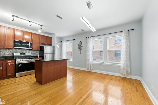 2611 W Rosemont Ave Unit A, Chicago, IL 60659 - kitchen with appliances with stainless steel finishes, dark countertops, light wood-style floors, and a kitchen island