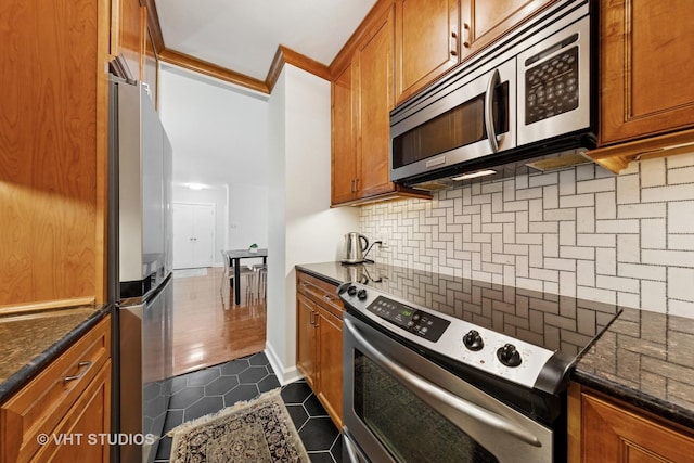 1325 N State Pkwy Unit 6D, Chicago, IL 60610 - kitchen with stainless steel appliances, brown cabinets, dark tile patterned floors, backsplash, and dark stone countertops