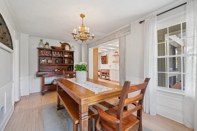 32 Valley Rd, Highland Park, IL 60035 - dining room featuring a chandelier, a decorative wall, light wood-style flooring, and wainscoting
