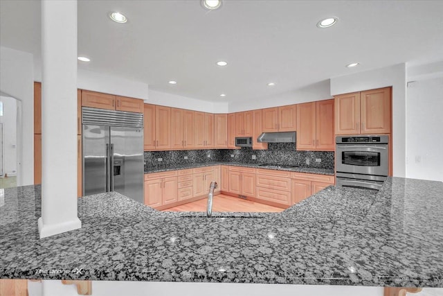 3550 E Ari Dr, Glenview, IL 60025 - kitchen featuring appliances with stainless steel finishes, under cabinet range hood, dark stone counters, decorative backsplash, and recessed lighting