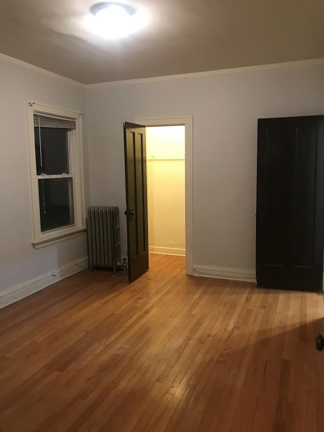 spare room featuring radiator heating unit, crown molding, and light wood-style flooring