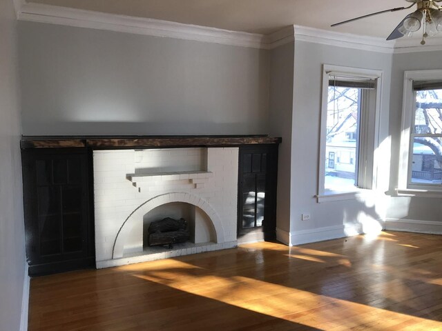 unfurnished living room featuring a fireplace, hardwood / wood-style flooring, crown molding, and ceiling fan