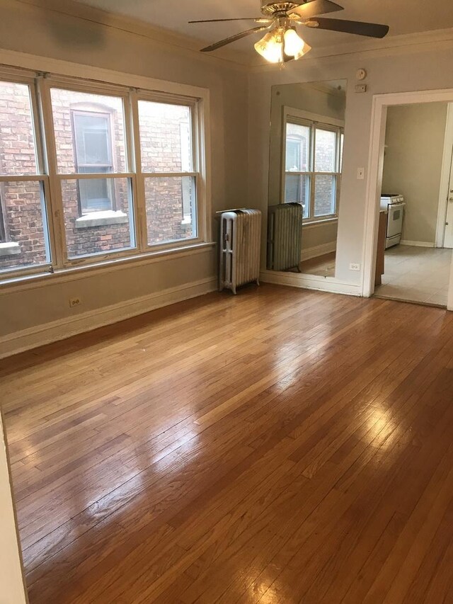 unfurnished room featuring radiator heating unit, ornamental molding, ceiling fan, and hardwood / wood-style flooring