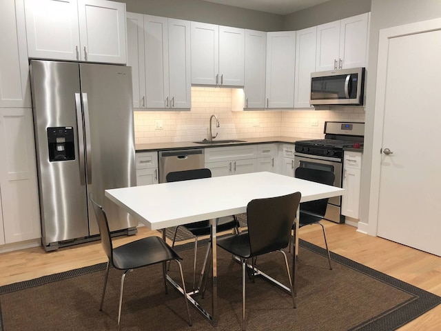 1017 S Claremont Ave, Chicago, IL 60612 - kitchen with stainless steel appliances, light wood finished floors, tasteful backsplash, a kitchen bar, and white cabinetry