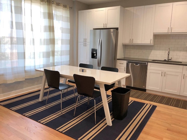 1017 S Claremont Ave, Chicago, IL 60612 - kitchen featuring appliances with stainless steel finishes, light wood finished floors, white cabinets, decorative backsplash, and dark countertops