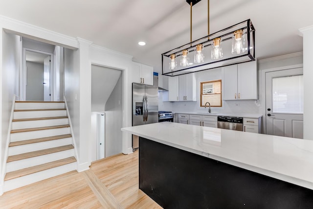 1441 Forest Rd, La Grange Park, IL 60526 - kitchen featuring stainless steel appliances, light wood finished floors, ornamental molding, pendant lighting, and white cabinets