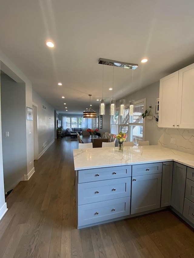 2142 N 73rd Ct, Elmwood Park, IL 60707 - kitchen featuring a peninsula, open floor plan, dark wood finished floors, light stone countertops, and pendant lighting