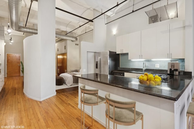 1000 W Washington Blvd Unit 320, Chicago, IL 60607 - kitchen with a towering ceiling, stainless steel fridge with ice dispenser, dark countertops, light wood-type flooring, and white cabinetry