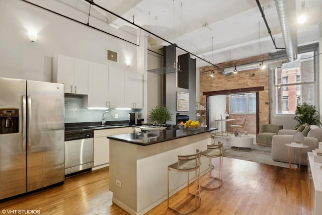1000 W Washington Blvd Unit 320, Chicago, IL 60607 - kitchen with stainless steel appliances, a towering ceiling, light wood-style floors, dark countertops, and open floor plan