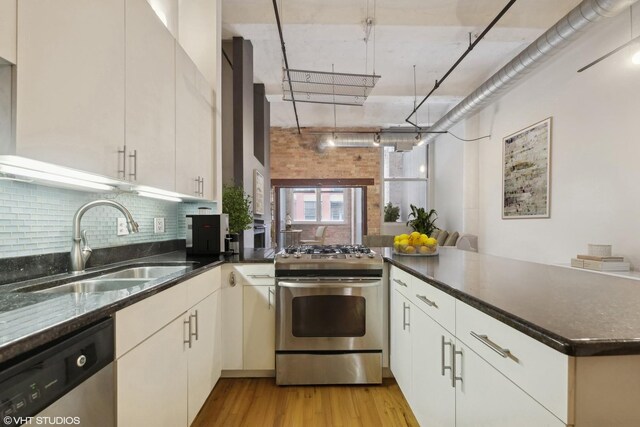 1000 W Washington Blvd Unit 320, Chicago, IL 60607 - kitchen featuring stainless steel appliances, a peninsula, backsplash, light wood-type flooring, and dark stone counters