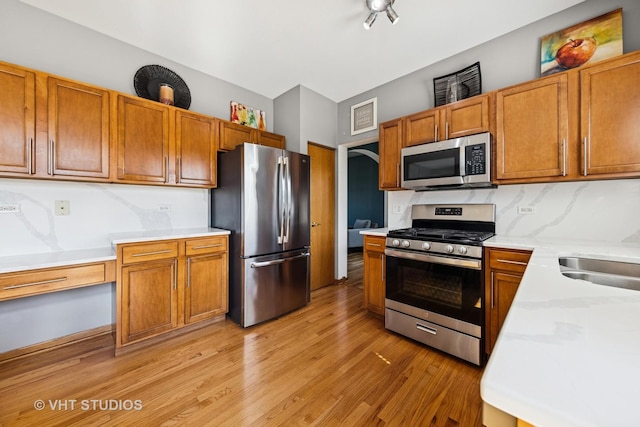 1581 Kenmore Ave, Aurora, IL 60505 - kitchen with appliances with stainless steel finishes, light wood-type flooring, light countertops, brown cabinetry, and tasteful backsplash