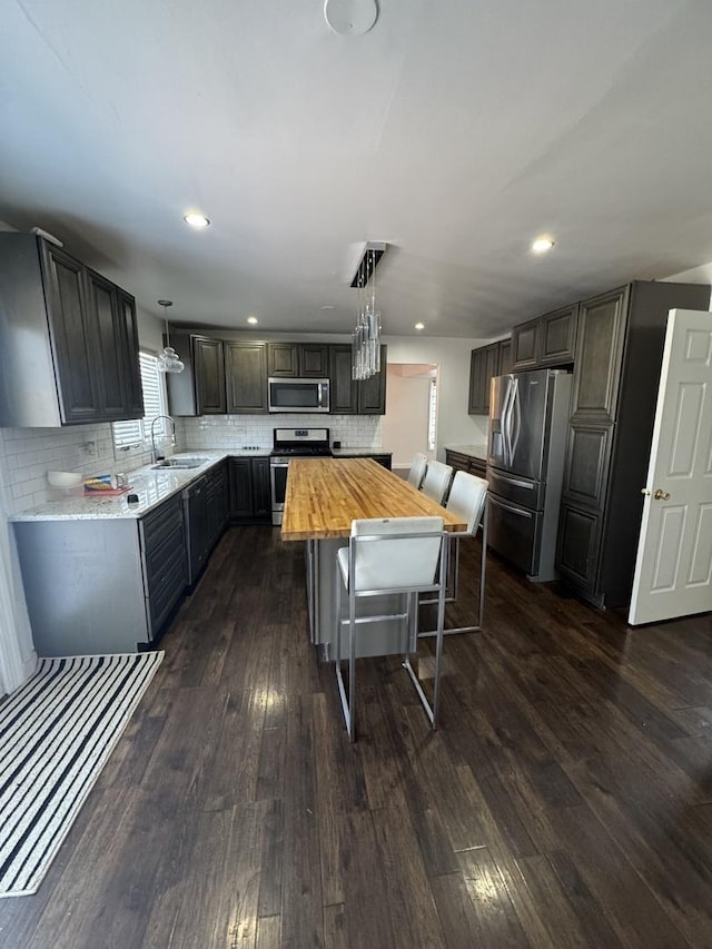 4550 Columbine Ln, Matteson, IL 60443 - kitchen featuring appliances with stainless steel finishes, wood counters, dark wood-type flooring, backsplash, and a center island