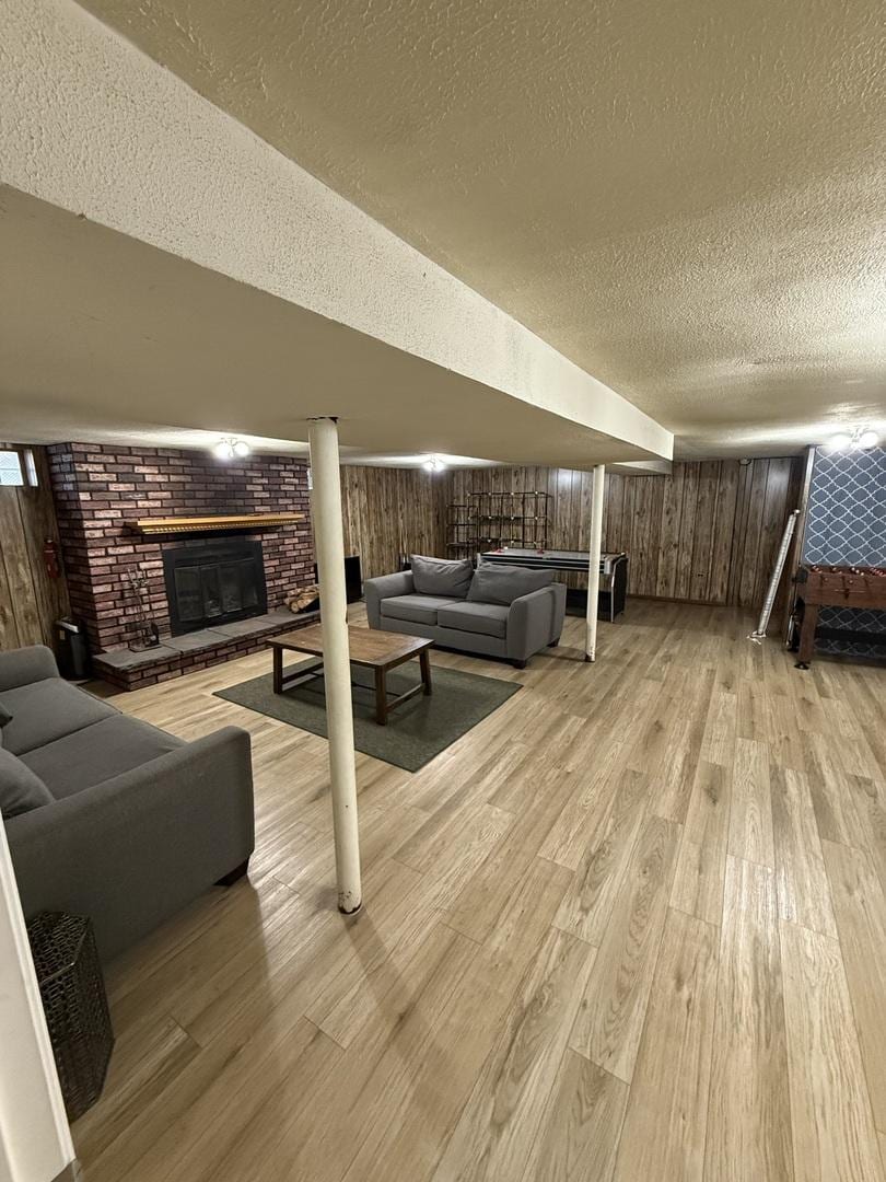 1369 Superior Ave, Calumet City, IL 60409 - living area featuring a textured ceiling, light wood-style floors, a brick fireplace, and wood walls