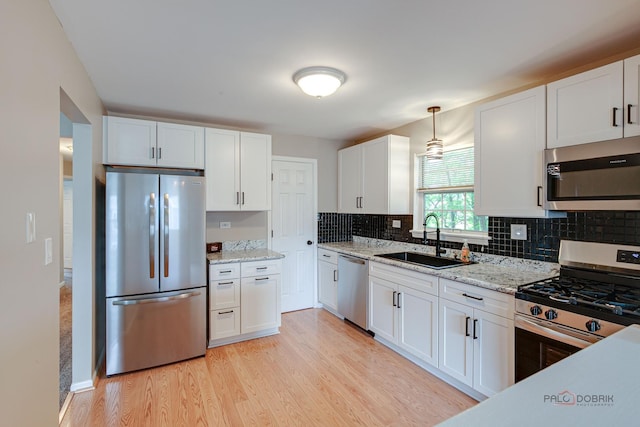 1186 Ballantrae Pl Unit D, Mundelein, IL 60060 - kitchen with appliances with stainless steel finishes, white cabinetry, light wood-style flooring, tasteful backsplash, and light stone countertops
