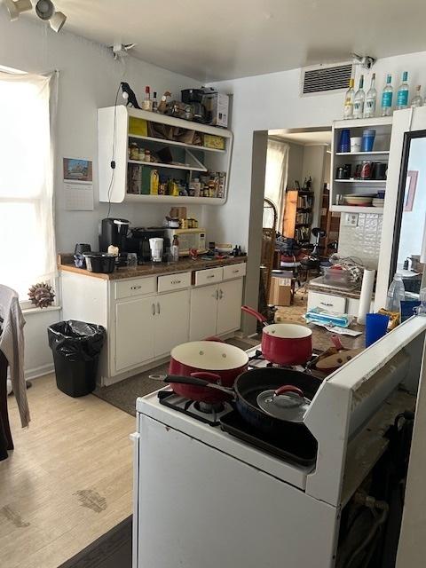 2431 W Thomas St, Chicago, IL 60622 - kitchen with stove, white cabinetry, light wood-type flooring, dark countertops, and open shelves