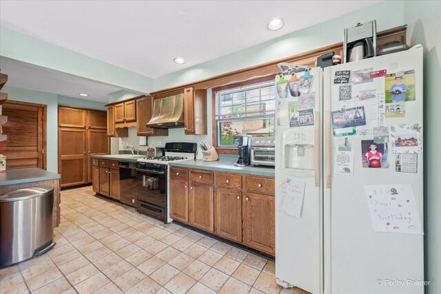 335 Arlington Rd, Itasca, IL 60143 - kitchen with white fridge with ice dispenser, gas range, wall chimney range hood, brown cabinetry, and recessed lighting