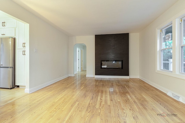 16705 Wolf Rd, Orland Park, IL 60467 - unfurnished living room with a large fireplace, arched walkways, and light wood-type flooring