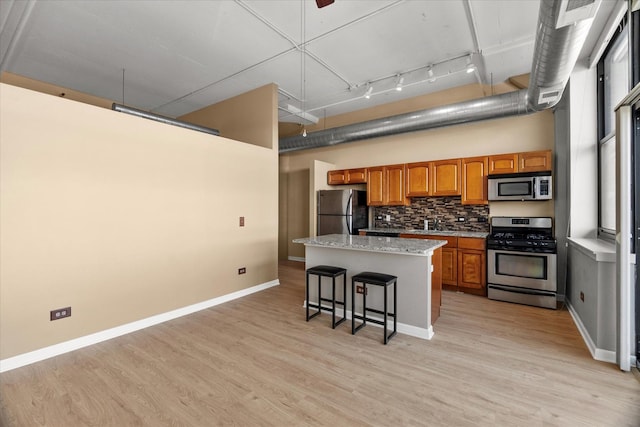 2323 W Pershing Rd Unit 212, Chicago, IL 60609 - kitchen featuring appliances with stainless steel finishes, brown cabinets, a center island, a towering ceiling, and a kitchen bar