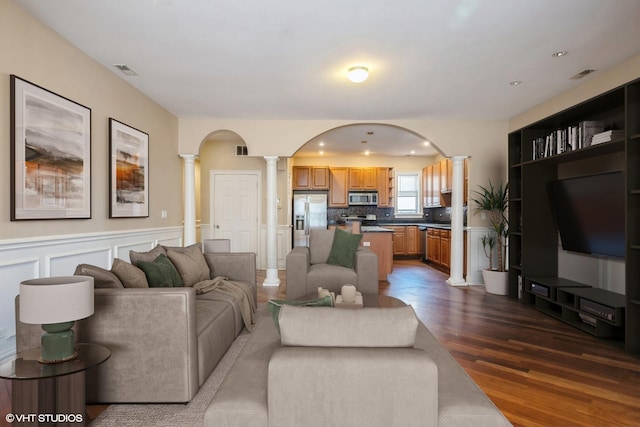 7018 S Paxton Ave Unit 3N, Chicago, IL 60649 - living room featuring decorative columns, dark wood-type flooring, a wainscoted wall, and a decorative wall