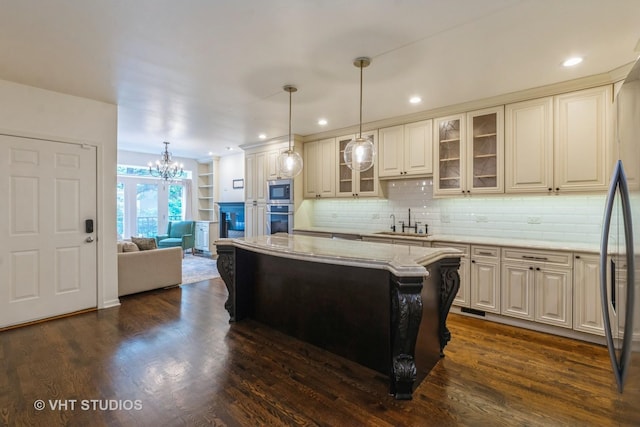 1302 N Bosworth Ave Unit 1, Chicago, IL 60642 - kitchen featuring stainless steel appliances, a center island, a chandelier, light stone countertops, and dark wood finished floors