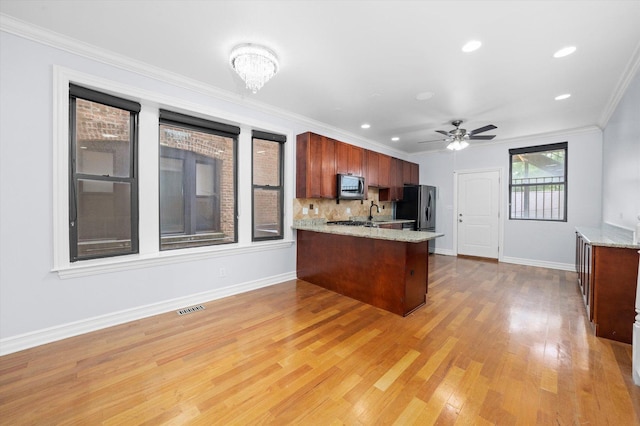 1363 E 64th St Unit 1, Chicago, IL 60637 - kitchen with stainless steel microwave, a peninsula, freestanding refrigerator, light wood-style flooring, and light stone counters