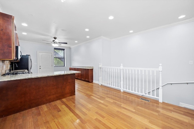 1363 E 64th St Unit 1, Chicago, IL 60637 - kitchen featuring appliances with stainless steel finishes, light wood finished floors, light stone counters, a ceiling fan, and a peninsula