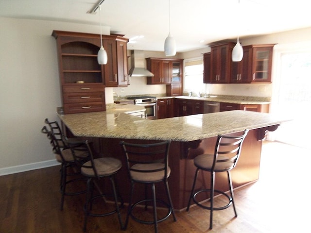 623 Willow Ln, Elk Grove Village, IL 60007 - kitchen with wall chimney range hood, appliances with stainless steel finishes, a peninsula, glass insert cabinets, and pendant lighting