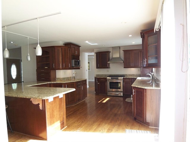 623 Willow Ln, Elk Grove Village, IL 60007 - kitchen featuring stainless steel appliances, wall chimney range hood, dark wood-style flooring, light stone counters, and a kitchen bar