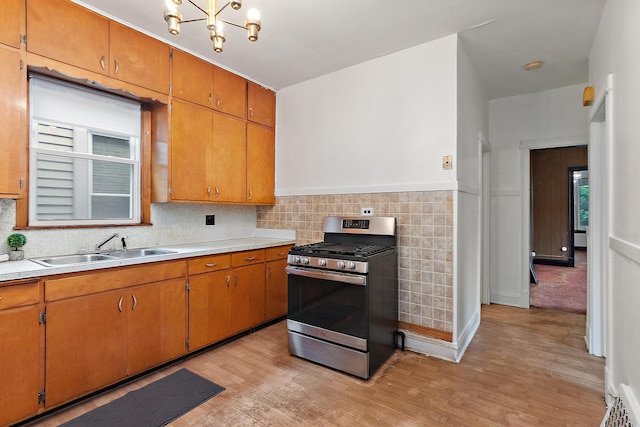 7933 S Burnham Ave, Chicago, IL 60617 - kitchen featuring stainless steel range with gas stovetop, light wood-style flooring, light countertops, a chandelier, and brown cabinets