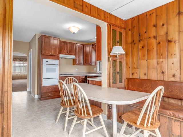 4923 W School St, Chicago, IL 60641 - kitchen featuring oven, a warming drawer, a kitchen breakfast bar, light countertops, and under cabinet range hood