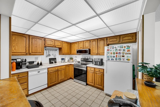 475 Plum Creek Dr Unit 212, Wheeling, IL 60090 - kitchen featuring appliances with stainless steel finishes, light countertops, brown cabinetry, a drop ceiling, and light tile patterned floors