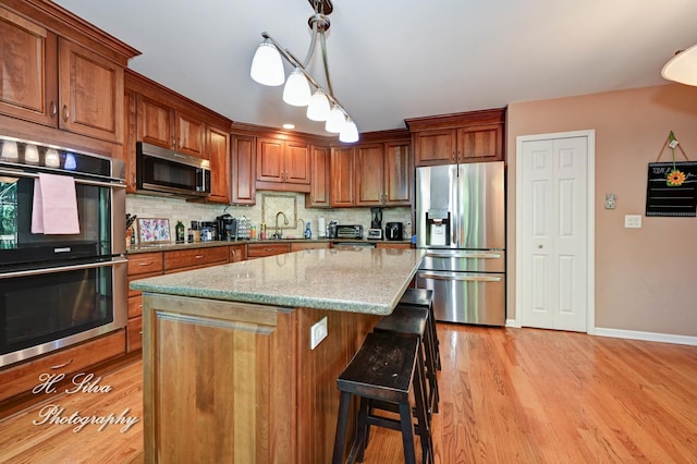 750 Seybrooke Ln, Crystal Lake, IL 60012 - kitchen featuring appliances with stainless steel finishes, light wood-style floors, a kitchen bar, backsplash, and light stone countertops