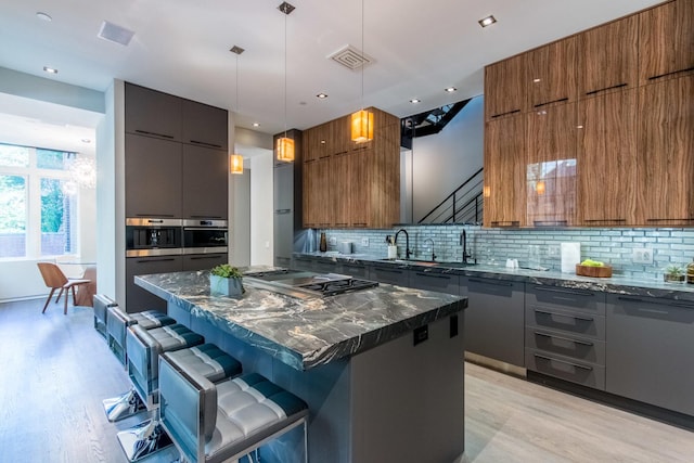 1401 N Astor St, Chicago, IL 60610 - kitchen featuring modern cabinets, light wood-style floors, stainless steel appliances, a breakfast bar, and brown cabinetry