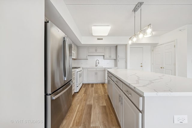 1 N Beacon Pl Unit 502, La Grange, IL 60525 - kitchen with freestanding refrigerator, white gas stove, light wood-style floors, decorative backsplash, and a center island