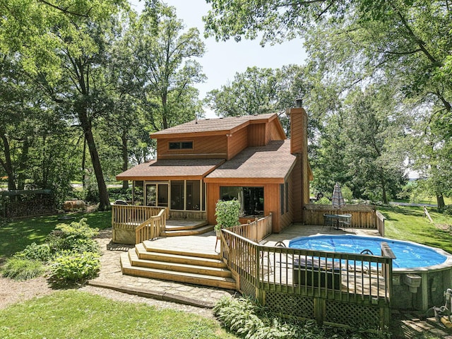 45W984 Mcdonald Rd, Hampshire, IL 60140 - back of property with a shingled roof, a wooden deck, an outdoor pool, a chimney, and view of wooded area