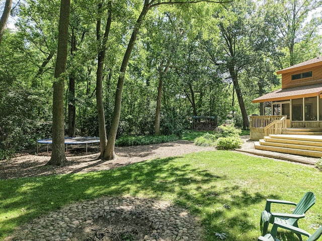 45W984 Mcdonald Rd, Hampshire, IL 60140 - view of green lawn with a trampoline, a sunroom, and a wooden deck