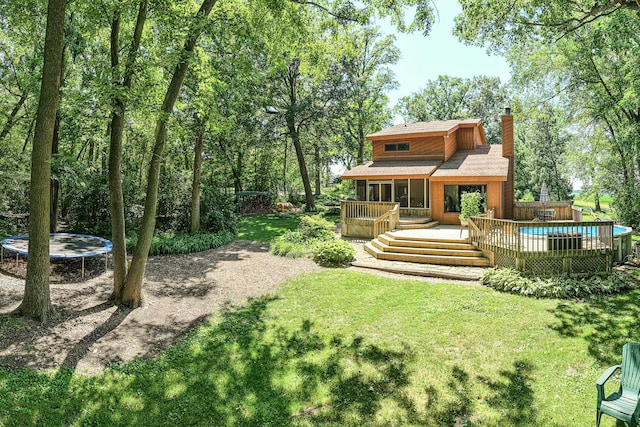 45W984 Mcdonald Rd, Hampshire, IL 60140 - rear view of house featuring a trampoline, a chimney, a wooden deck, an outdoor pool, and a yard