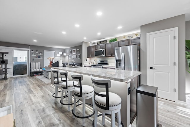 2493 Alison Ave, Pingree Grove, IL 60140 - kitchen featuring appliances with stainless steel finishes, light countertops, dark brown cabinetry, a breakfast bar, and an island with sink