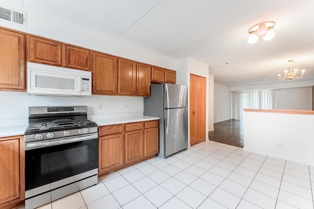 8710 W Evelyn Ln Unit 201, Chicago, IL 60656 - kitchen featuring appliances with stainless steel finishes, brown cabinets, light countertops, and a chandelier