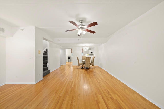 1036 Susan Collins Ln, Oak Park, IL 60302 - spare room with stairs, light wood-style flooring, ceiling fan, and a chandelier