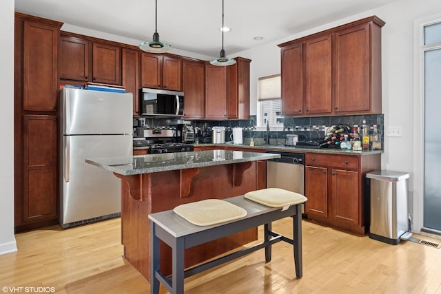 2321 S Wabash Ave Unit 12, Chicago, IL 60616 - kitchen featuring appliances with stainless steel finishes, light wood-style floors, tasteful backsplash, dark stone countertops, and a center island