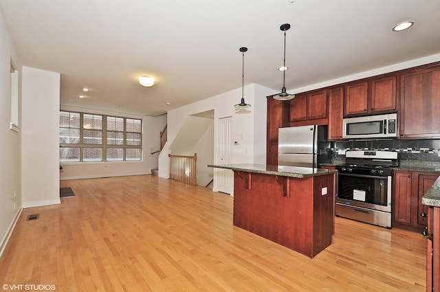 2321 S Wabash Ave Unit 12, Chicago, IL 60616 - kitchen with stainless steel appliances, a kitchen island, tasteful backsplash, light wood-type flooring, and a breakfast bar
