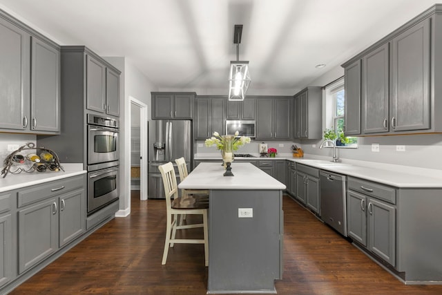 802 Barton Dr, Oswego, IL 60543 - kitchen featuring stainless steel appliances, gray cabinetry, a breakfast bar, a kitchen island, and light countertops