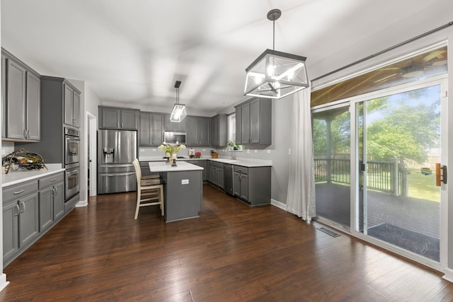 802 Barton Dr, Oswego, IL 60543 - kitchen with appliances with stainless steel finishes, gray cabinetry, a center island, a breakfast bar, and light countertops