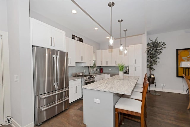 609 E 48th St, Chicago, IL 60615 - kitchen with stainless steel appliances, a center island, dark wood-style floors, a breakfast bar area, and white cabinets