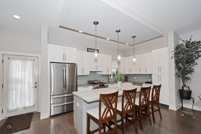609 E 48th St, Chicago, IL 60615 - kitchen with appliances with stainless steel finishes, a kitchen island, a kitchen bar, dark wood-style flooring, and white cabinets