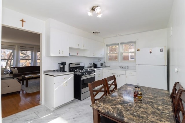 8914 La Crosse Ave Unit 2S, Skokie, IL 60077 - kitchen featuring freestanding refrigerator, stainless steel range with gas stovetop, light marble finish flooring, and white cabinetry