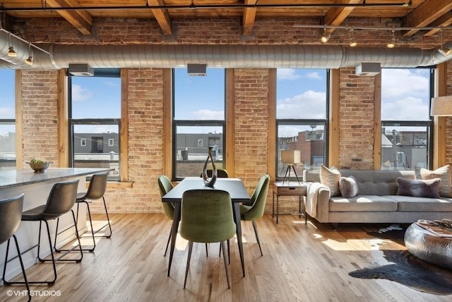2511 W Moffat St Unit 305-D, Chicago, IL 60647 - dining area featuring beamed ceiling, wood finished floors, healthy amount of natural light, and brick wall